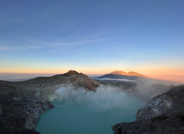 Un cratère volcanique aux eaux turquoise, entouré d’un paysage accidenté et avec une montagne en arrière-plan. 4