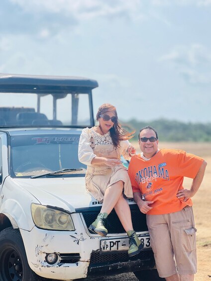 Two people sitting on a white SUV with a damaged front bumper and a license plate reading 'WP PT 83'. 3