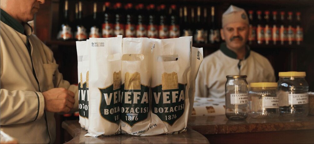 A bar with bags of Bozaçisi 1876 beer and jars of liquor on the counter. 3