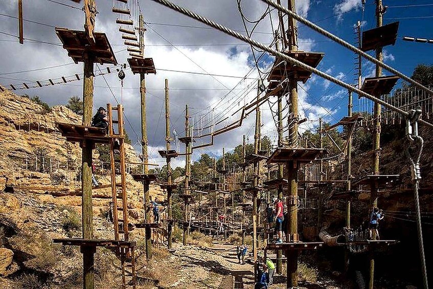 An outdoor obstacle course with wooden platforms and ropes set against a rocky landscape. 2