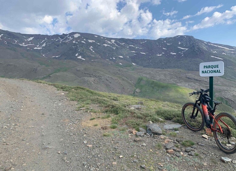 A mountain landscape with a sign reading 'PARQUE NACIONAL' and a mountain bike parked on the side. 2