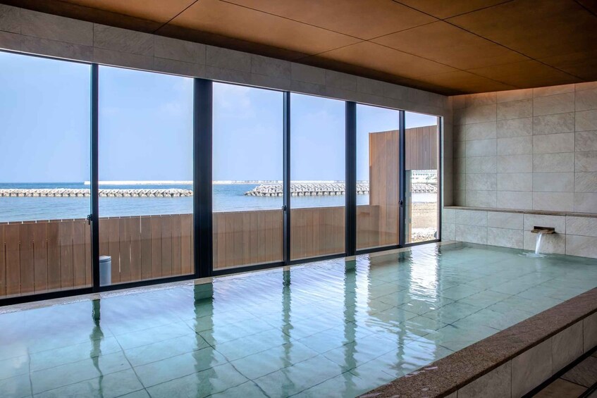 A modern indoor swimming pool with large windows overlooking the sea. 4