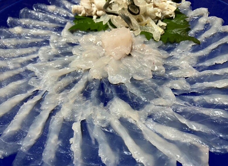 A plate of sashimi with a central piece of fish and garnishes. 3