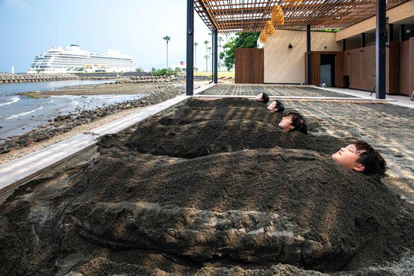 Two people lying in a sandpit with a cruise ship in the background. 5