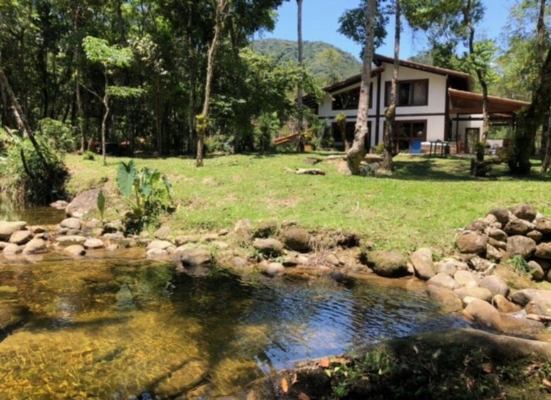 A house surrounded by a natural landscape with a clear stream. 1