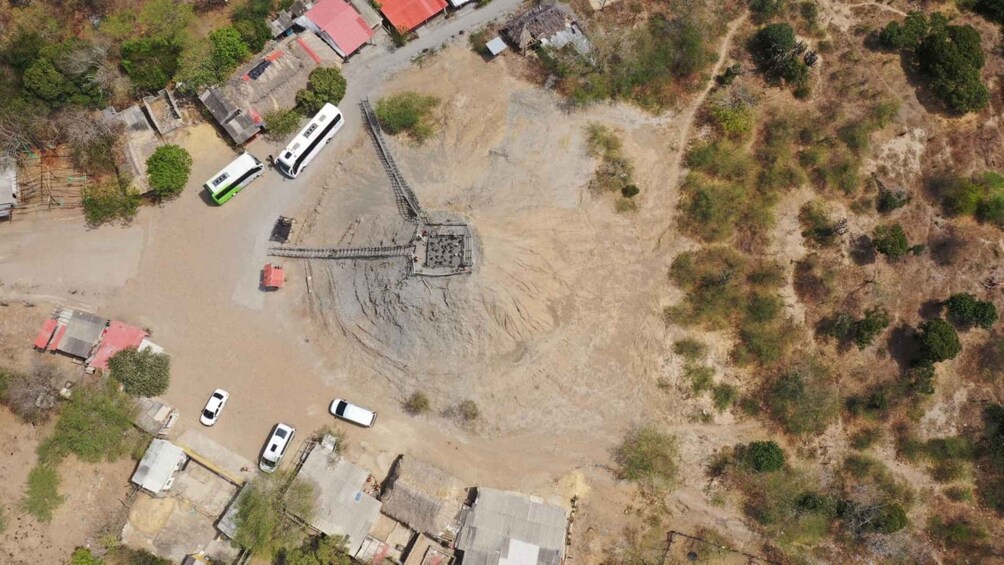 An aerial view of a construction site with a large excavation pit, several parked vehicles, and surrounding buildings. 4