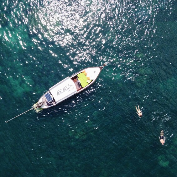 A boat with a person swimming nearby. 2