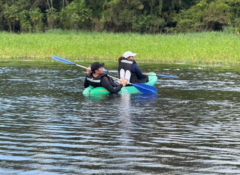 Two people kayaking on a calm river surrounded by greenery. 4