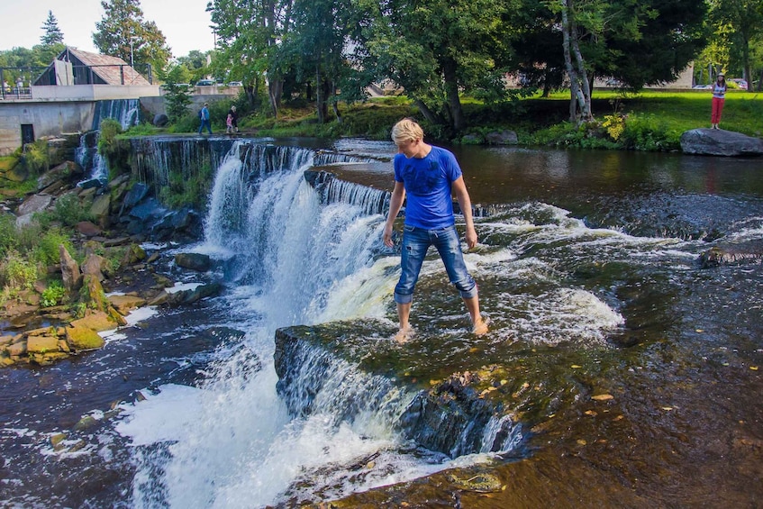 A waterfall in a park with a person standing on a rock. 5