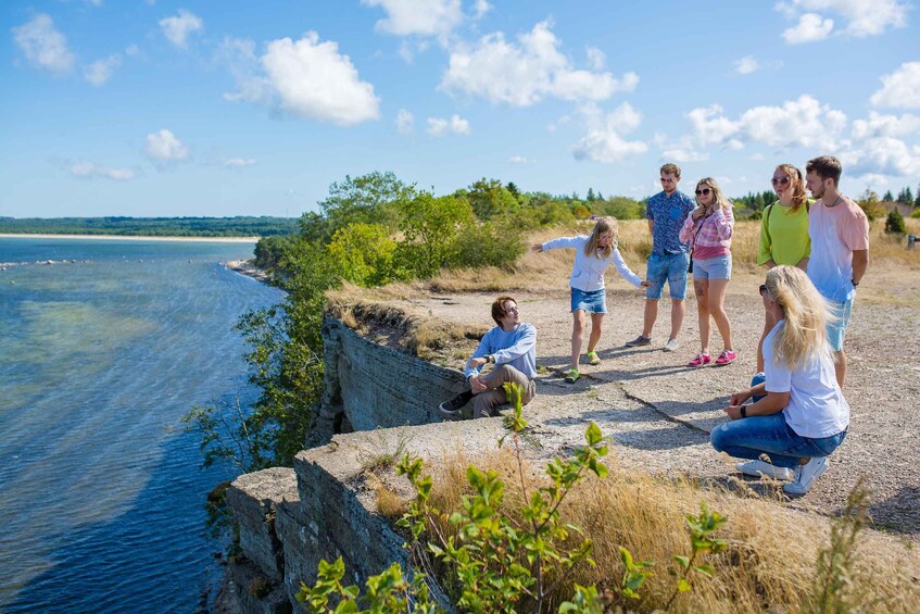 A group of people by a coastal cliff overlooking a body of water. 2