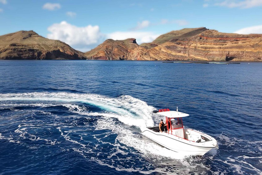 A speedboat on a body of water with a mountainous landscape in the background. 3
