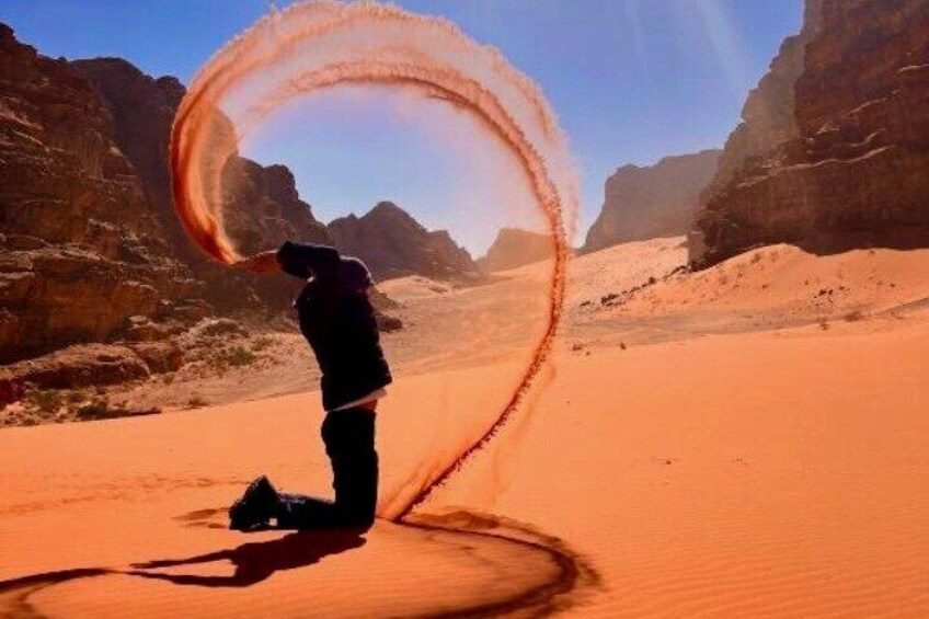 A person in a desert with a large circular sand formation. 3