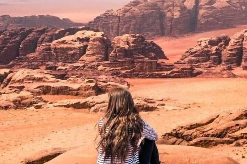 A person standing in a desert with red rock formations in the background. 2