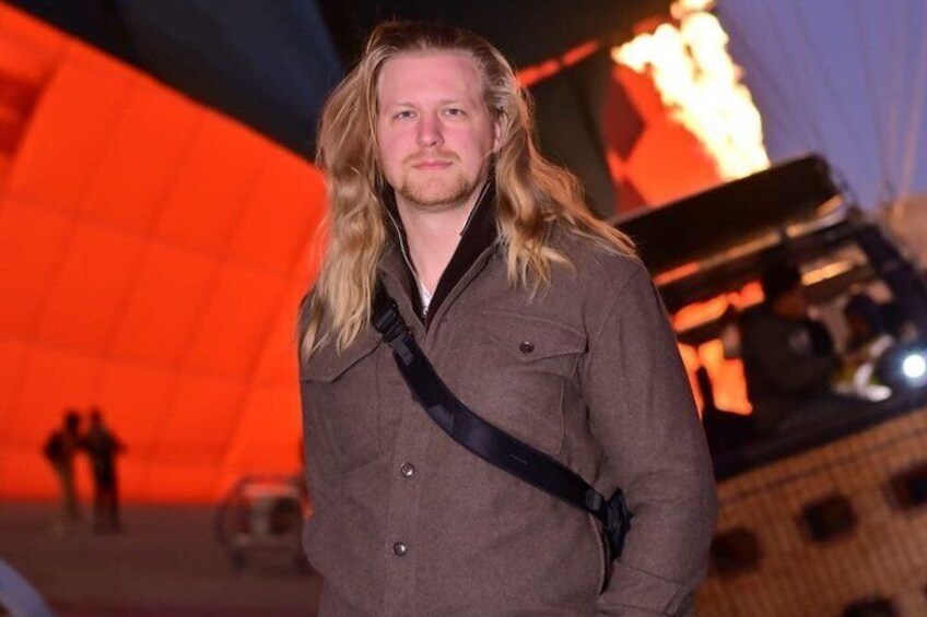 A person standing in front of a large, illuminated structure with a geometric design. 5