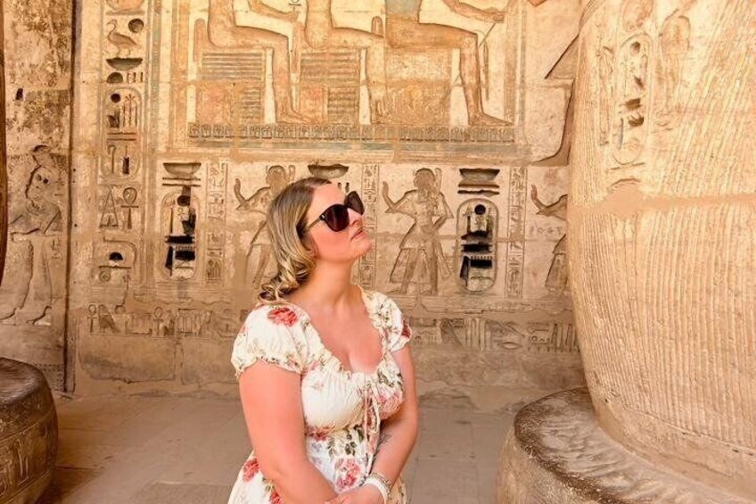 A person standing in front of ancient Egyptian hieroglyphs on a stone wall. 2