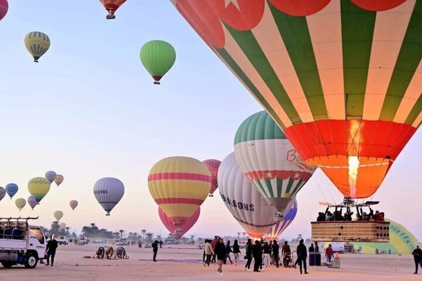 A hot air balloon festival with multiple balloons in the sky and a crowd on the ground. 3