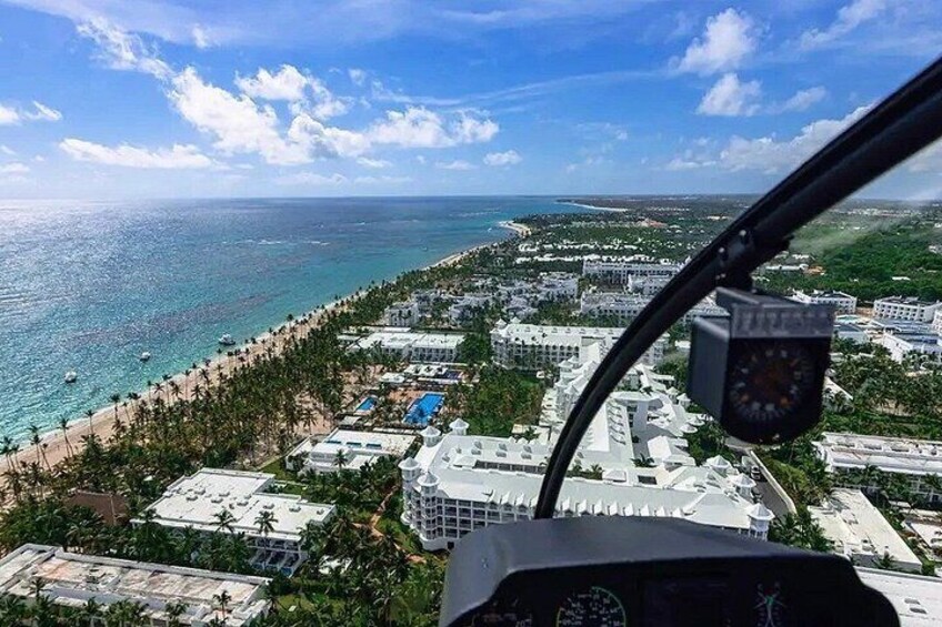 A helicopter view of a coastal area with a beach, buildings, and a clear sky. 2