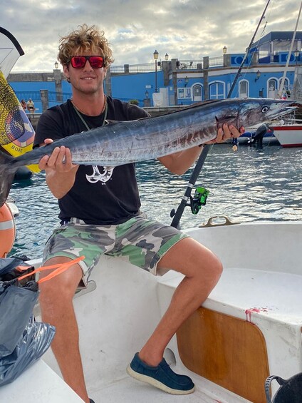 A person holding a large fish on a boat. 3
