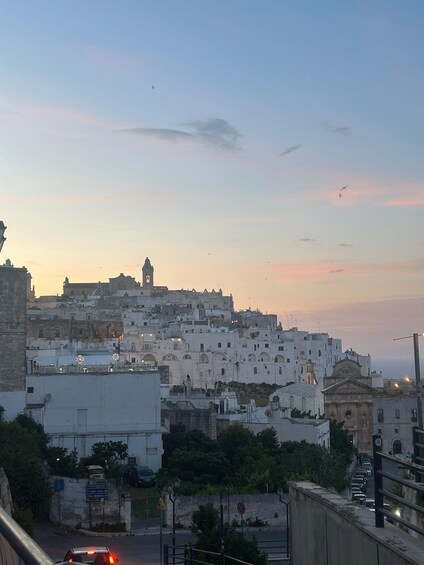 A cityscape with white buildings, a prominent clock tower, and a clear sky. 1