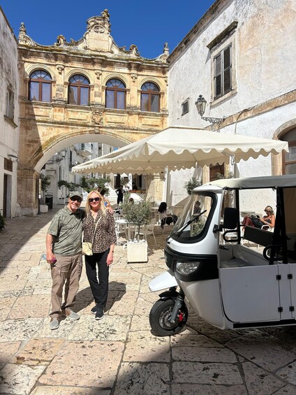 A couple standing in a historic courtyard with a white canopy and a parked golf cart. 5