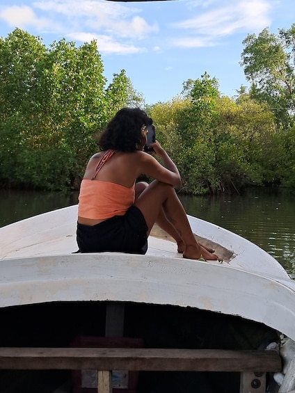 A person sitting on a boat, holding a phone. 1