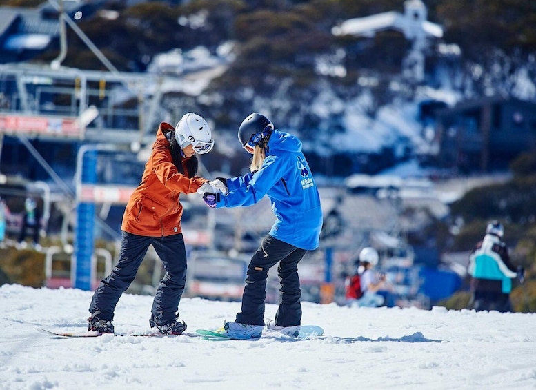 Two snowboarders in a snowy area with a ski lift in the background. 1
