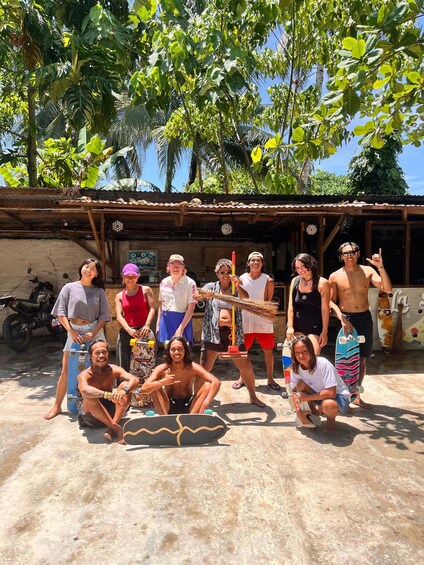 A group of people posing in front of a rustic building with a motorcycle parked nearby. 2