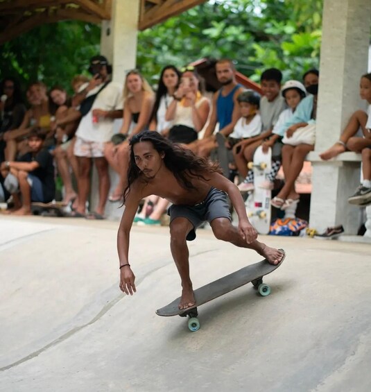 A person skateboarding on a concrete surface with an audience in the background. 3