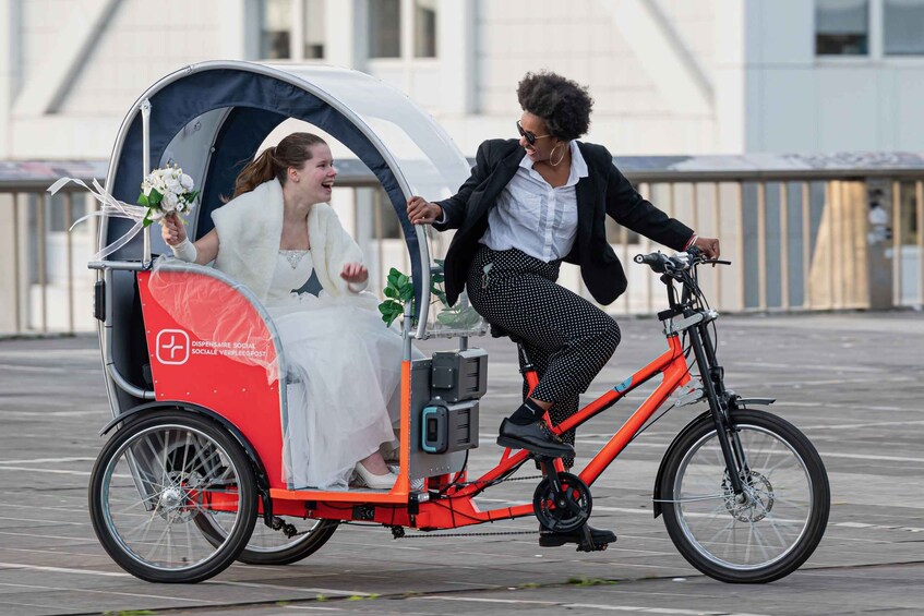 A person on a bicycle with a canopy, another person in a wedding dress, and a building in the background. 4