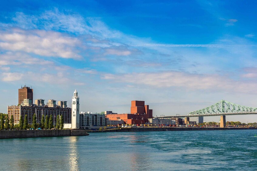 A city skyline with a prominent clock tower, a green bridge, and a calm river. 4