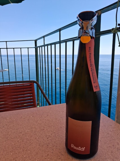 A bottle of Kombucha Sparkling Tea on a table with a view of the ocean. 1