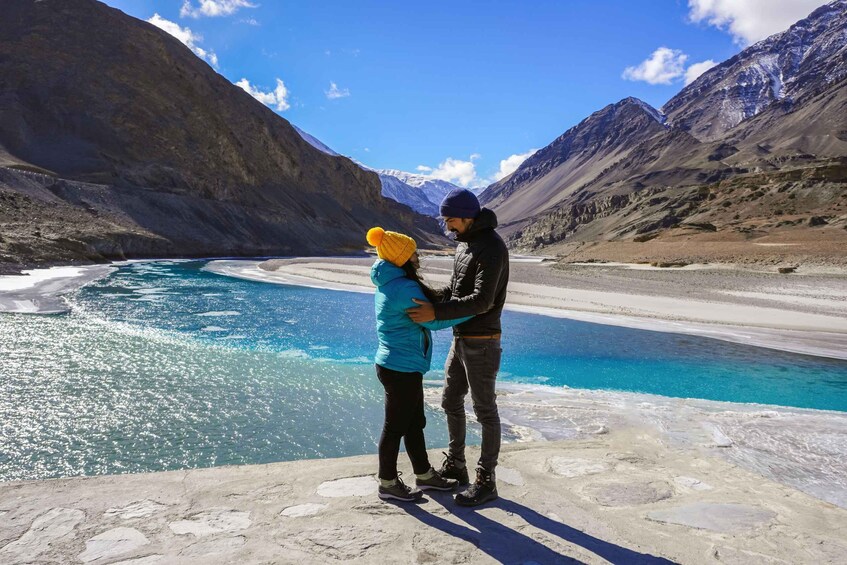 Two people embracing by a glacial lake with mountains in the background. 3