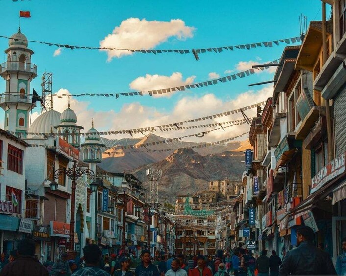 A bustling street with traditional architecture, a prominent minaret, and a mountainous backdrop. 4