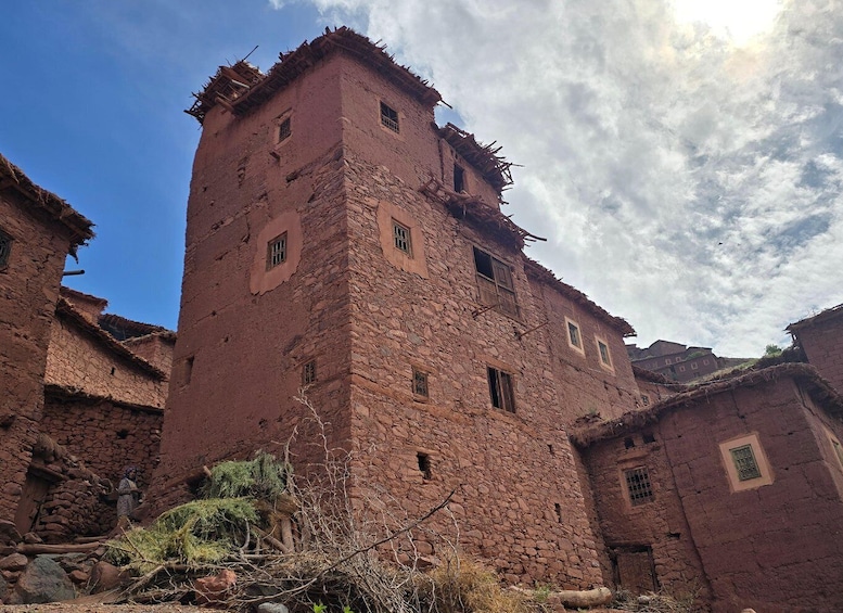 A red brick tower with multiple windows and a thatched roof, surrounded by traditional buildings. 1