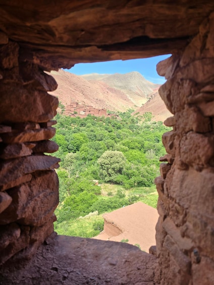 A view through a stone archway overlooking a lush valley with mountains in the background. 5