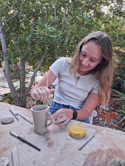 A person working on pottery at an outdoor table. 3