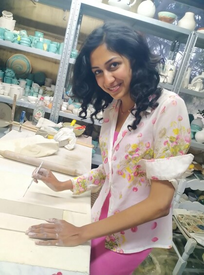 A person working with clay on a table in a pottery workshop. 2