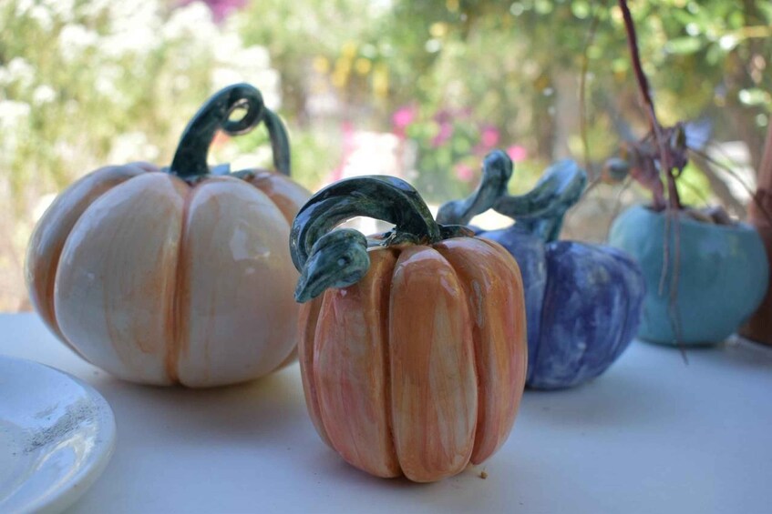 Ceramic pumpkins with handles, in various colors, on a table. 1