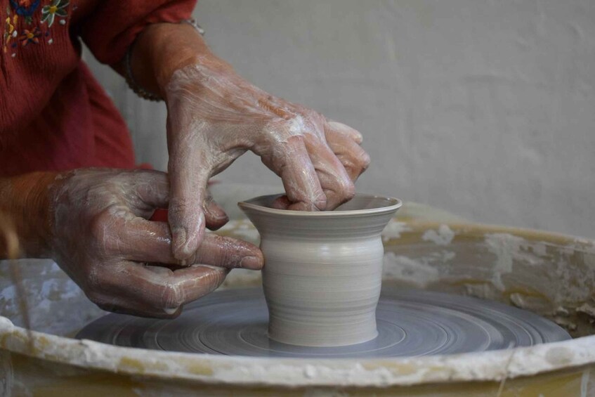 Hands shaping a clay pot on a pottery wheel. 5