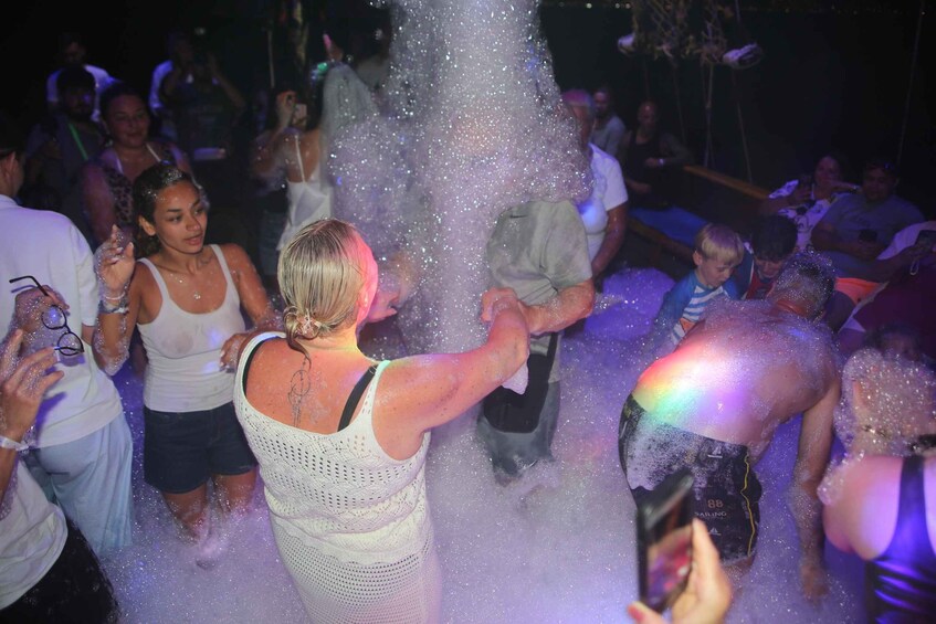 A group of people at a party, some standing and some sitting, with water being sprayed at them. 2