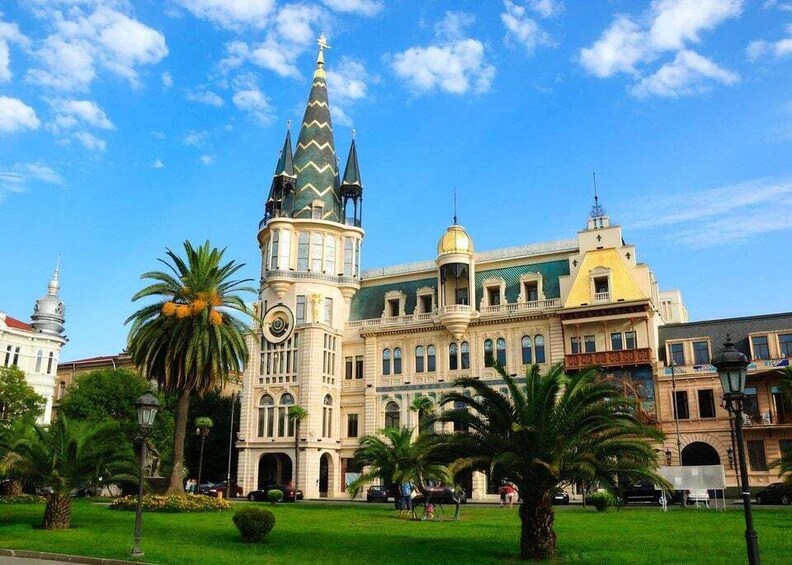 A historic building with a clock tower and a dome, surrounded by palm trees and a clear blue sky. 3