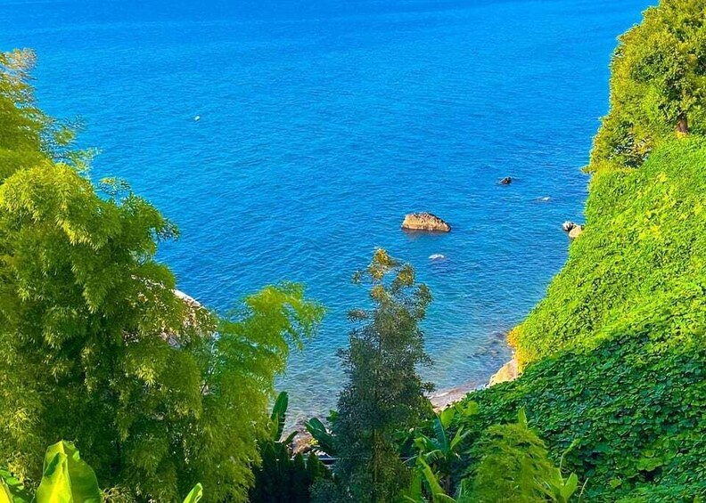 A coastal landscape with clear blue waters, green foliage, and rocky outcrops. 2