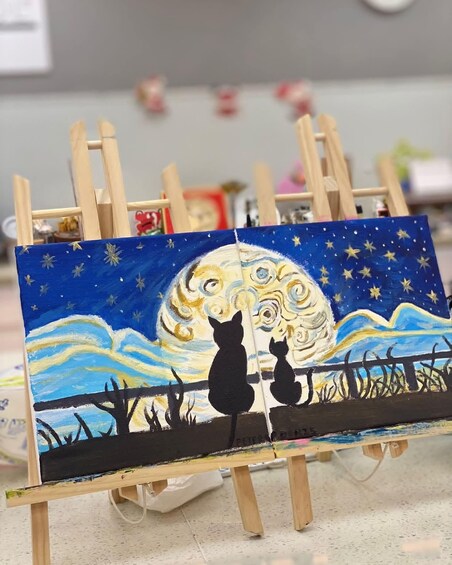 An easel with a painting of a cat and a dog gazing at a moonlit night sky. 5