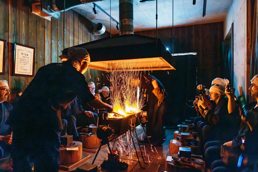 A chef cooking with sparks flying under a large hood in a rustic kitchen setting. 1