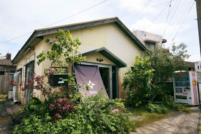 A house with a purple banner, a vending machine, and lush greenery. 2