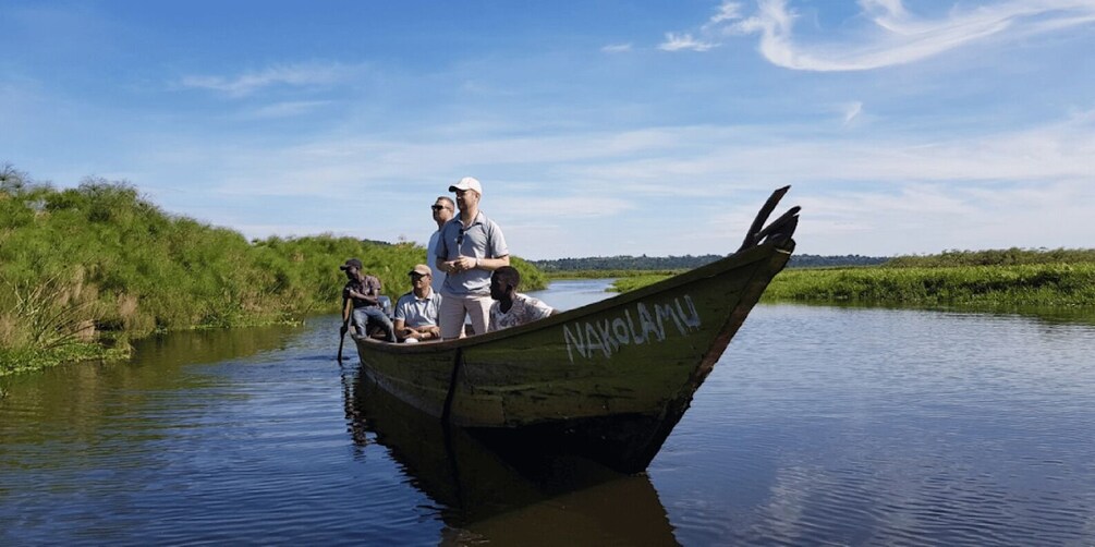 A boat named 'NAKOLAMU' on a calm river with greenery on the banks. 1