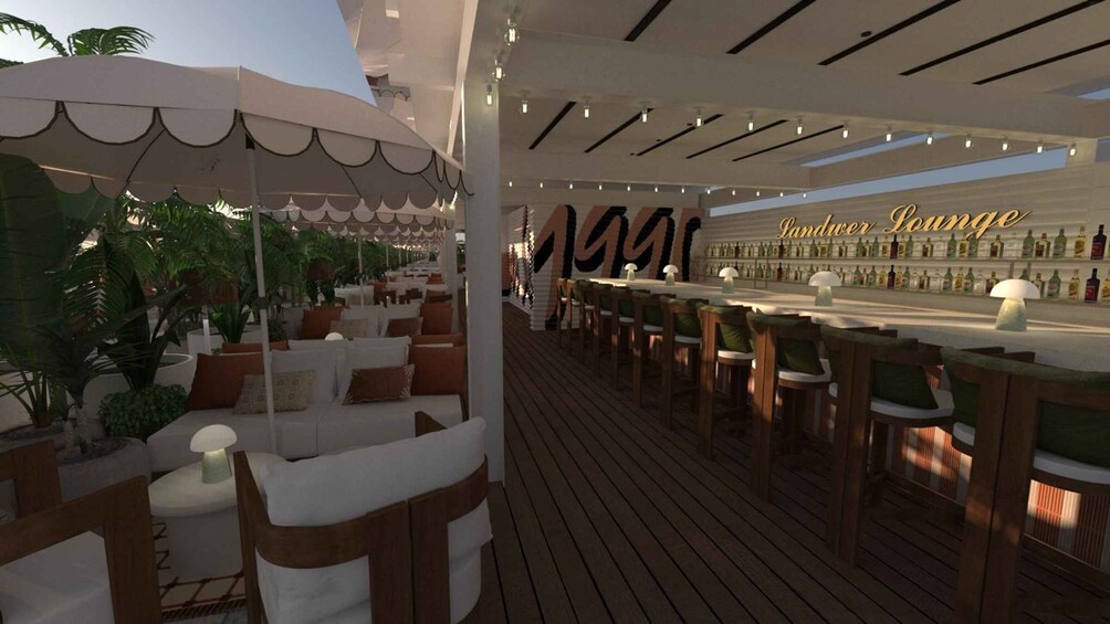 An outdoor bar area with wooden flooring, white cushioned seating, and a large umbrella. 4
