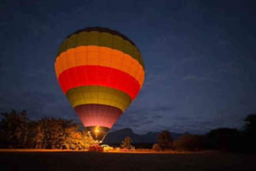 A hot air balloon with multiple colored panels descending at dusk. 3