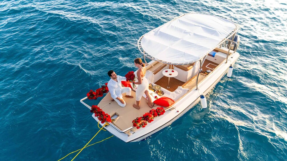 A boat with a white canopy, red flowers, and a man and woman in wedding attire. 2
