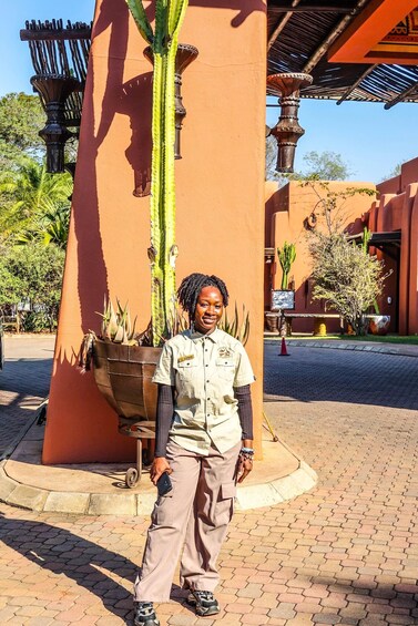 A person standing in front of a large cactus planter, with a building and a street lamp in the background. 3